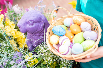 Fototapeta na wymiar Easter decorations. a rabbit figure next to Easter eggs in a basket, on green grass, on a windy day.