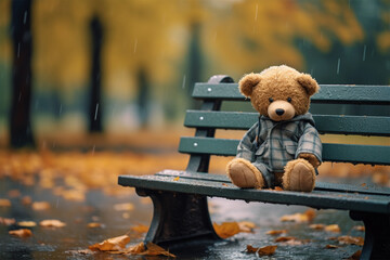 Lonely bear in a plaid shirt on a park bench, lost and alone in a rainy park. Loneliness concept, International Missing Children's Day