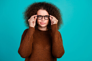 Portrait of funky chevelure curls hair lady in brown pullover touching glasses during checkup her...
