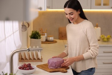 Happy woman packing bowl into beeswax food wrap at countertop in kitchen