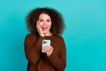 Photo portrait of pretty young girl excited hold gadget impressed wear trendy brown outfit isolated on cyan color background