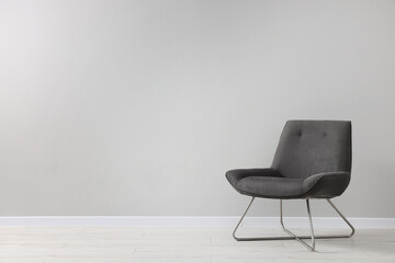 Comfortable armchair near light grey wall indoors. Space for text - obrazy, fototapety, plakaty
