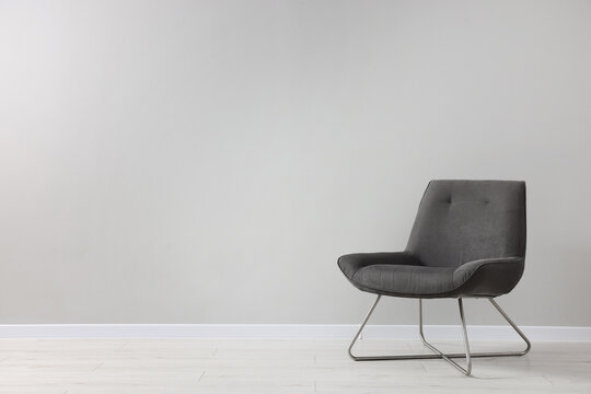 Comfortable armchair near light grey wall indoors. Space for text