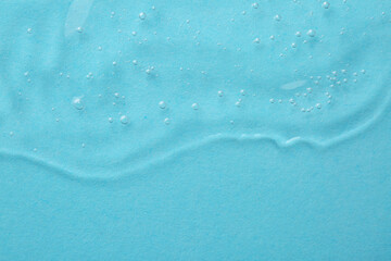 Clear cosmetic serum on light blue background, top view. Space for text