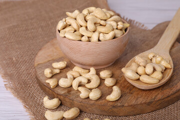 Tasty cashew nuts in bowl and spoon on table
