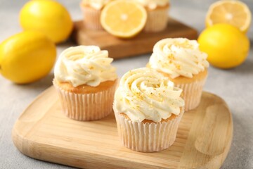 Tasty cupcakes with cream, zest and lemons on light grey table