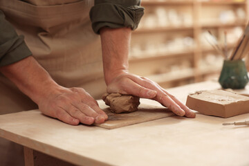 Man crafting with clay at table indoors, closeup