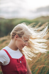 profile portrait of a  girl with long blond hair in a field of wheat