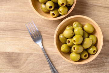 Pickled olives, Pitted green olives in wooden bowl, Table top view