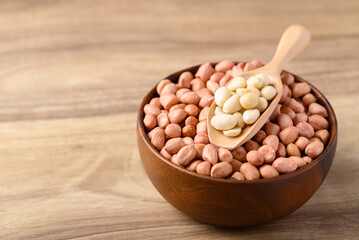 Peanut in bowl with spoon on wooden background