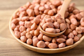 Peanut in bowl with spoon on wooden background