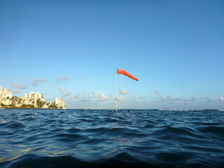 Flag pole with wind sock rises above the wavy waters of Waikiki