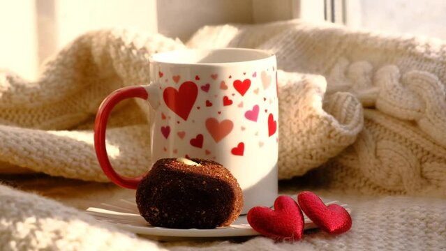 Cup of coffee and sweet chocolate ball cake, romance atmospheric mood, two  red hearts, knitted warm plaid  and sunlight. Breakfast for Valentines Day