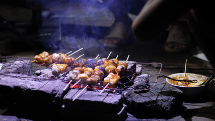 Close up video, making grilled meatballs, a traditional Indonesian food, which is skewered using...
