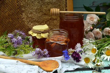 Still life with natural honey in jar, dipper, flowers and stick on wooden background outside....
