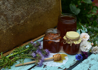 Still life with natural honey in jar, dipper, flowers and stick on wooden background outside. Countryside summer rural background, vintage concept, healthy food