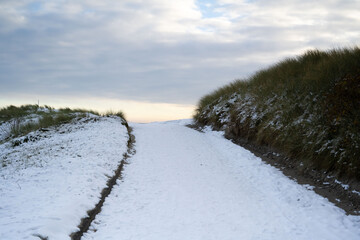 Fototapeta na wymiar A snowy snow path leads to the North Sea