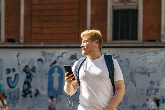 Young albino man using smartphone in the city