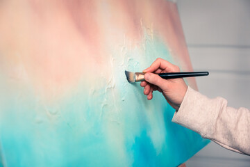 A closeup of an abstract painting with an artist applying brush strokes to the canvas. Textured...