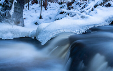 Blue hour by natural stream in the forest in Finland in winter