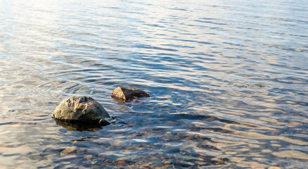 Seashore with round stones and calm water