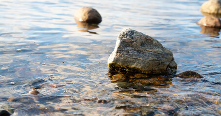Seashore with round stones and calm water