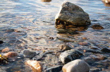 Seashore with round stones and calm water