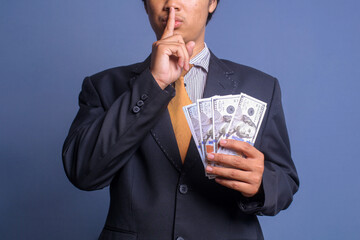 Man in suit put finger on lips showing keep silence gesture while holding money. Corruption and...