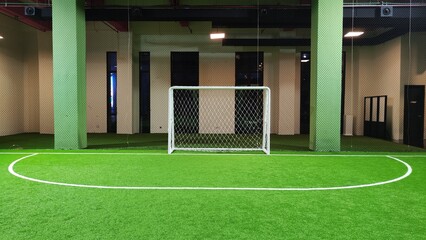Soccer goal net on indoor soccer field with white border on artificial green grass