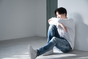 Handsome man sitting and relaxing by a window with beautiful shadows Image of melancholy, stress and worries