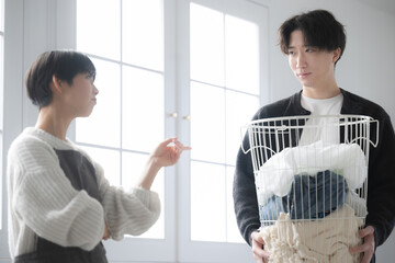 洗濯物を運ぶ夫と家事が遅いのでイライラする嫁と怒られる夫