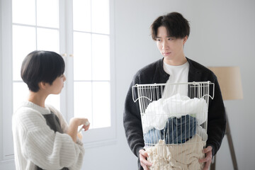 洗濯物を運ぶ夫と家事が遅いのでイライラする嫁と怒られる夫