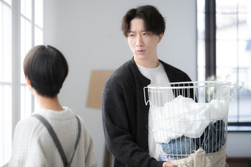 洗濯物を運ぶ夫と家事が遅いのでイライラする嫁