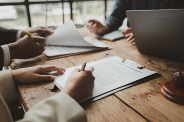 Business people negotiating a contract, discussing contract while working together in sunny modern office, unknown businessman and woman with colleagues or lawyers at meeting.