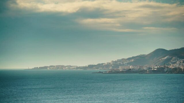 Seaside landscape. Timelapse of clouds moving over coast with Nerja town, Malaga province, Costa Del Sol, Andalusia, Spain.