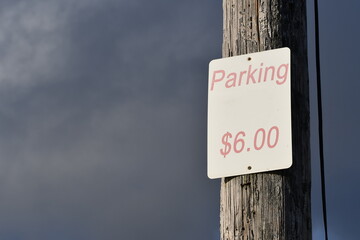 Pay for parking sign mounted on wooden pole. $6.00