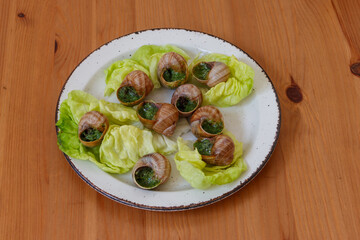 Escargots de Bourgogne (snails) seasoned with butter, parsley, garlic on wooden table