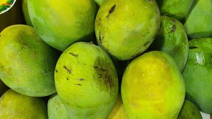 Close up pile of tasty fresh mangoes sold at the market as a background.