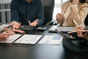 diverse group of Asian professionals, including middle-aged and mature individuals, gathered around a table in a business setting, discussing documents with focused attention.