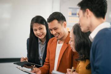 Asian business professionals team actively engaged in collaborative meeting in boardroom, sharing opinions and working together with visible happiness.