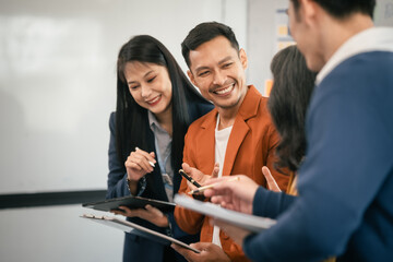 Asian business professionals team actively engaged in collaborative meeting in boardroom, sharing opinions and working together with visible happiness.