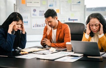 Fototapeta premium Asian colleagues in a boardroom, looking at a tablet with excited and joyful expressions, indicating a successful moment rather than stress.