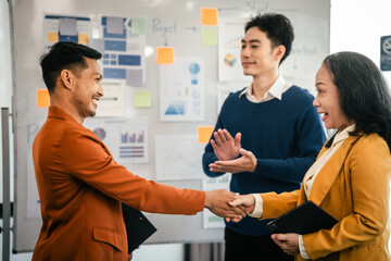 Obraz premium Asian middle-age man and mature woman professionals engaged in boardroom meeting. presents data from clipboard to his colleagues, suggesting annual review or planning session.