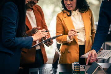 Asian real estate team engaged in a discussion, with two men and a woman focusing on a house model on a table, suggesting a planning or sales meeting.