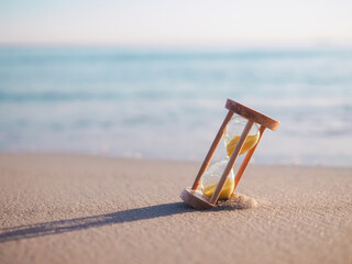 Hourglass on the beach in the sunset time. The concept about countdown to Summer, Travel, Vacation and Relaxation. © maybeiii