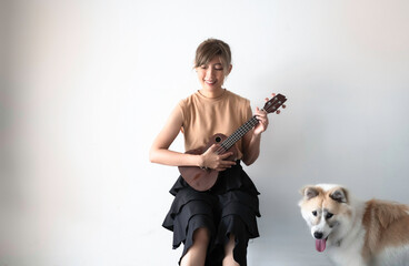 Woman playing Ukulele and her dog listining beside with interested feeling,