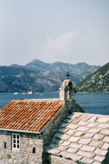 Church of Our Lady of Angels on the shore of the Bay of Kotor with the mountains in the background. Montenegro
