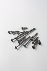 set of scattered metal screws isolated on neutral grey background, drywall screws with black...