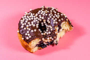Bitten donut with chocolate glaze on top isolated on a pink background