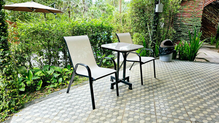 A set of tables and chairs to relax in the balcony with nature background. Metal desk and chair on...